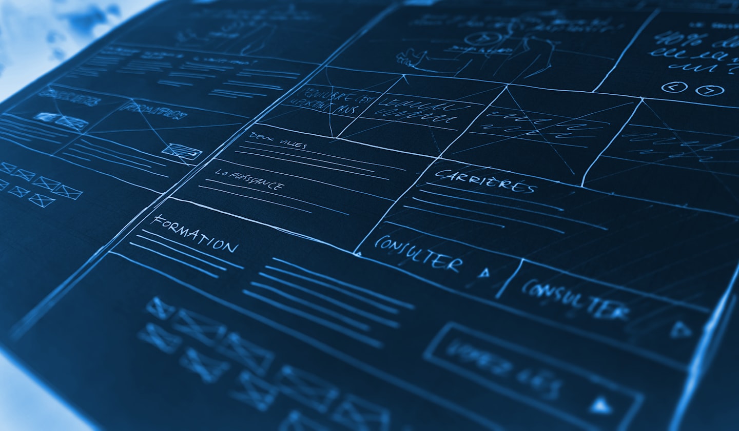 Diseño de wireframe de sitio web dibujado a mano con líneas blancas sobre una superficie oscura.
